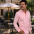 Man wearing a pink shirt standing outdoors as a wedding guest in a perfect dress shirt